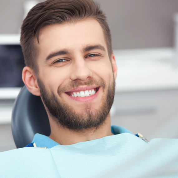 Patient holding up a dental shade guide guide to her teeth